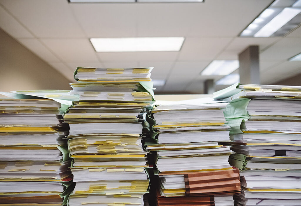 Large stacks of paper files and documents in an office.